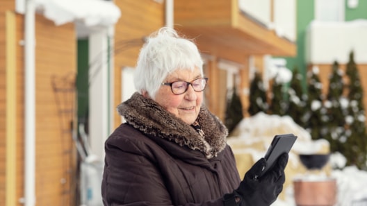 elderly woman looking at mobile phone outdoors