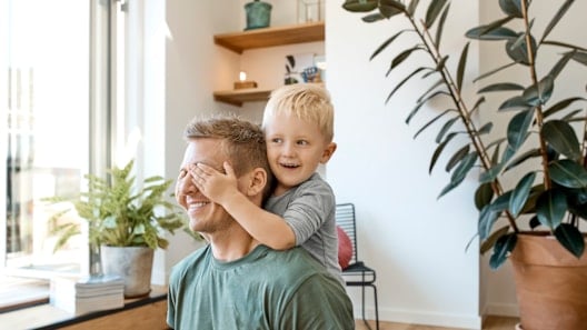 Smiling boy covering eyes of father