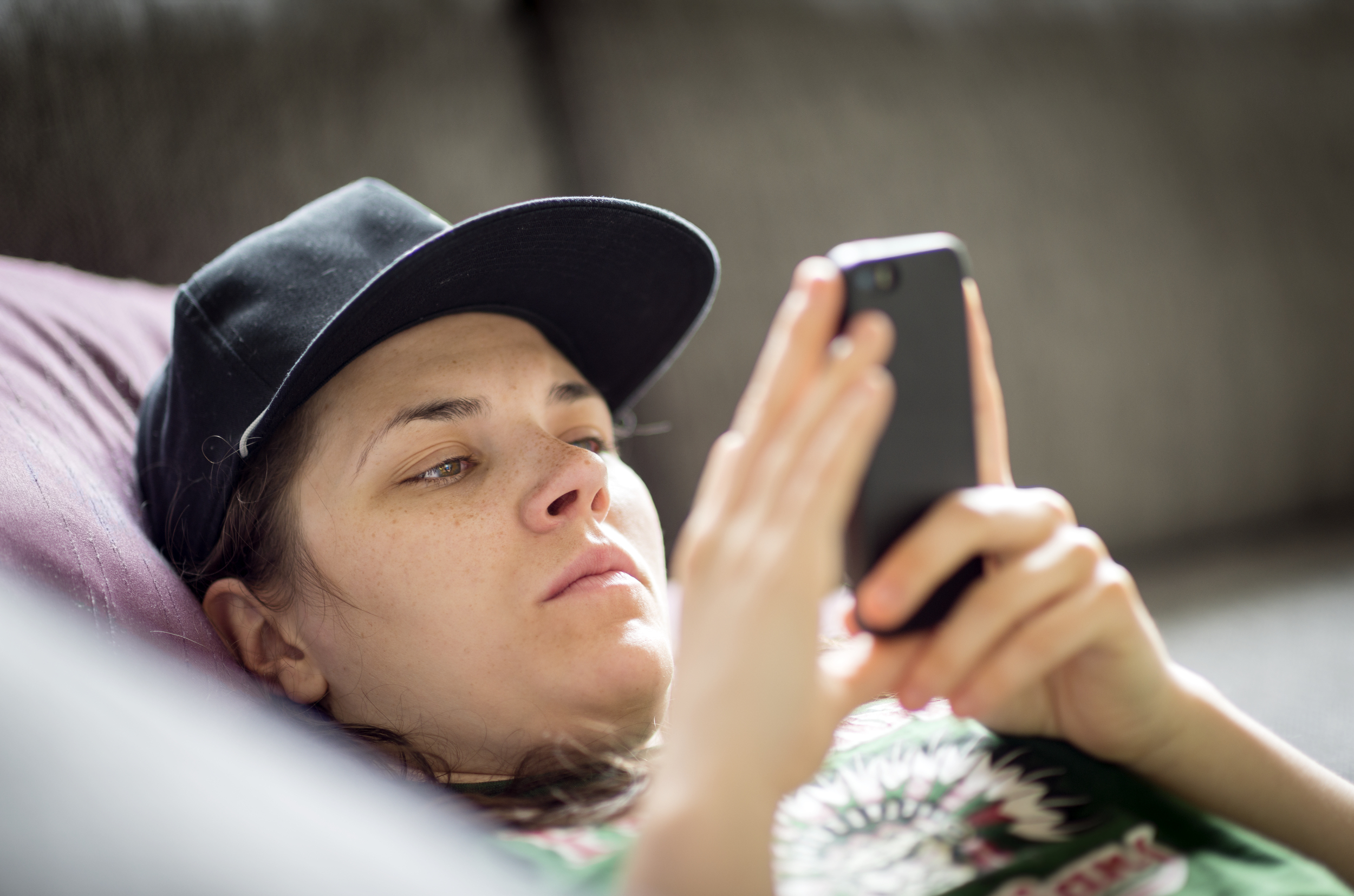 Person with cap and serious face looking at mobile phone