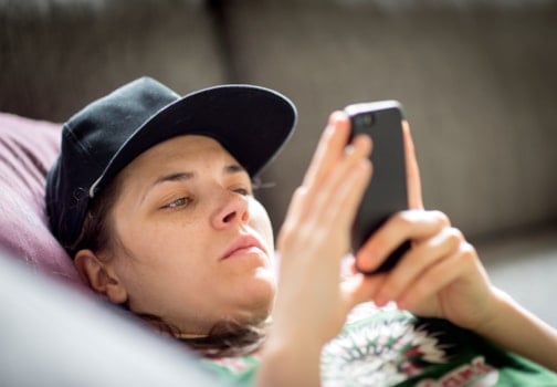 Person with cap and serious face looking at mobile phone