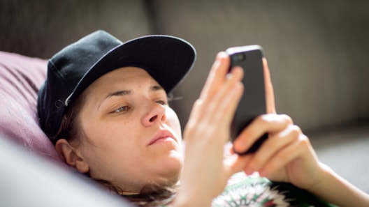 Person with cap and serious face looking at mobile phone
