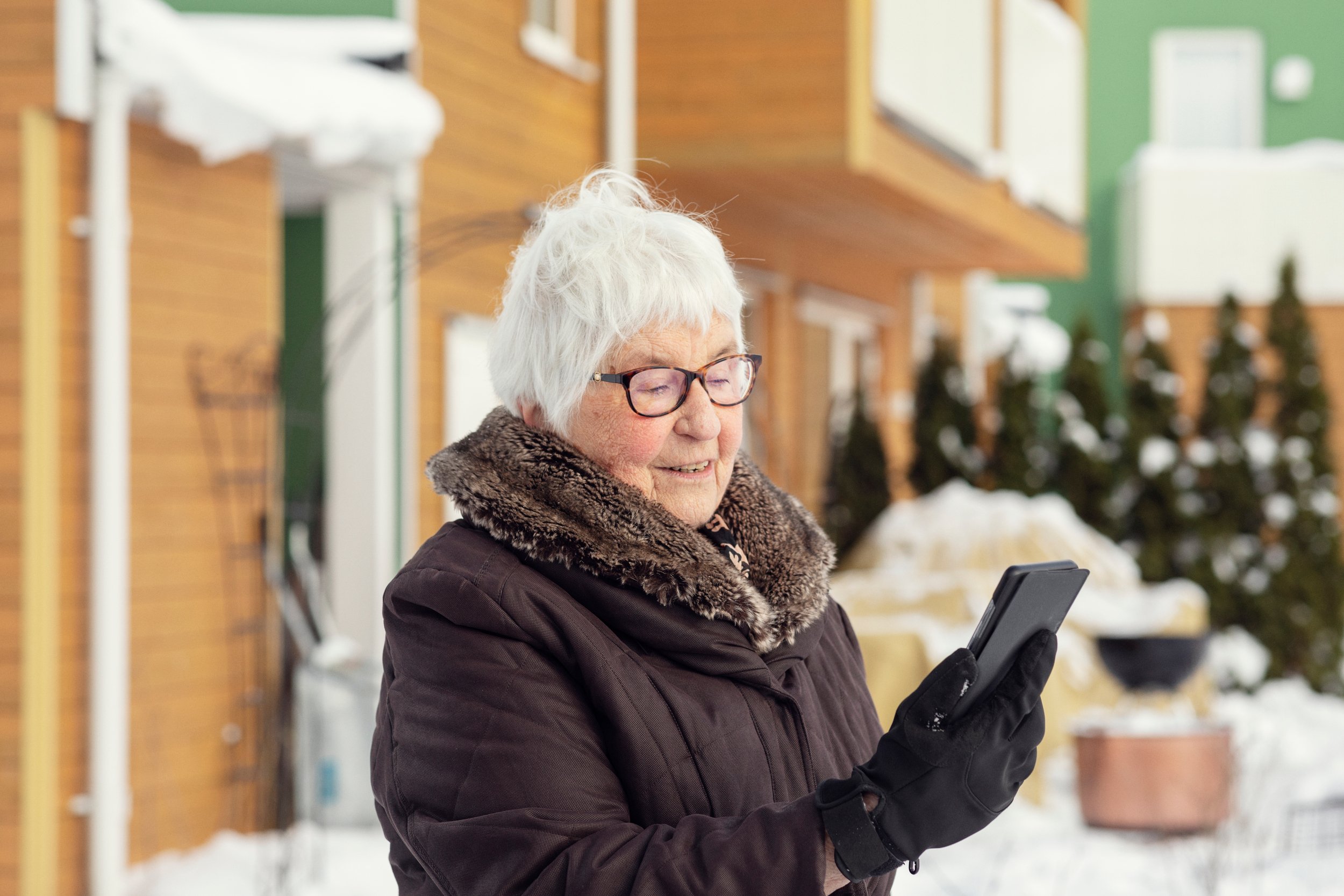 Elderly woman looking down at a mobile telephone outdoor