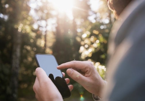 Man hands holding smartphone outdoors
